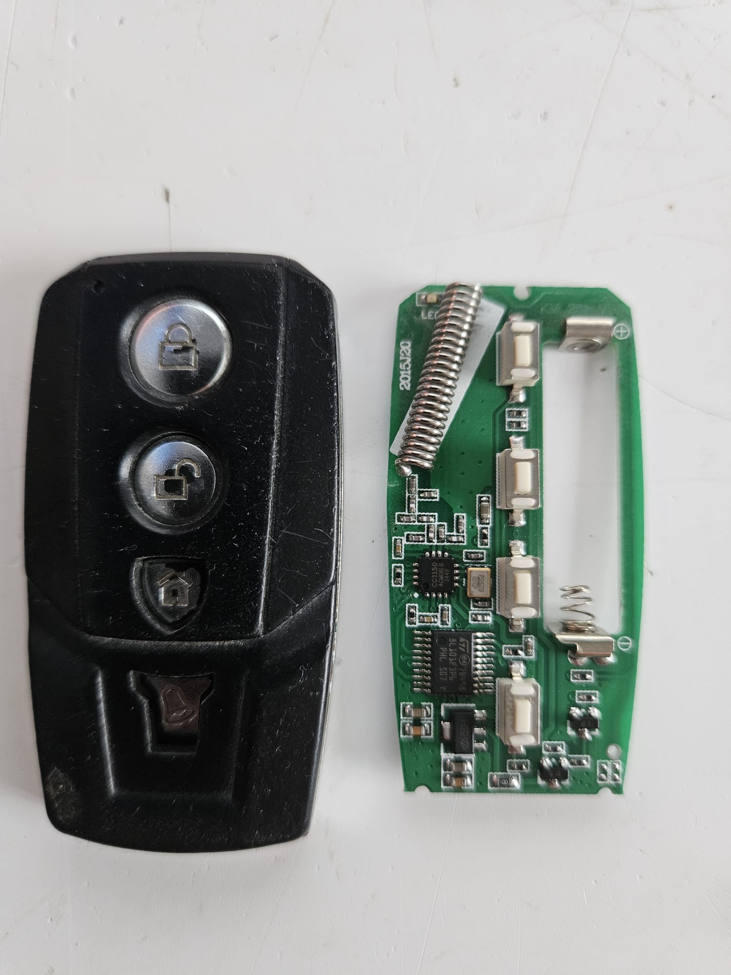 Alarm remote: fob case and opened PCB, coloured markers on the four button solder points